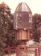 Sepia-toned lens with conical top, curved glass panels, and clockwork mechanism at the base.